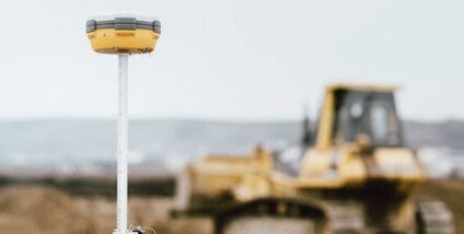 GPS rover receiver on site with earthmoving equipment on grade behind