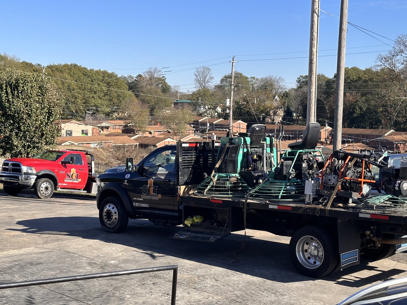 Company flatbed trucks loaded with finishing equipment heading out