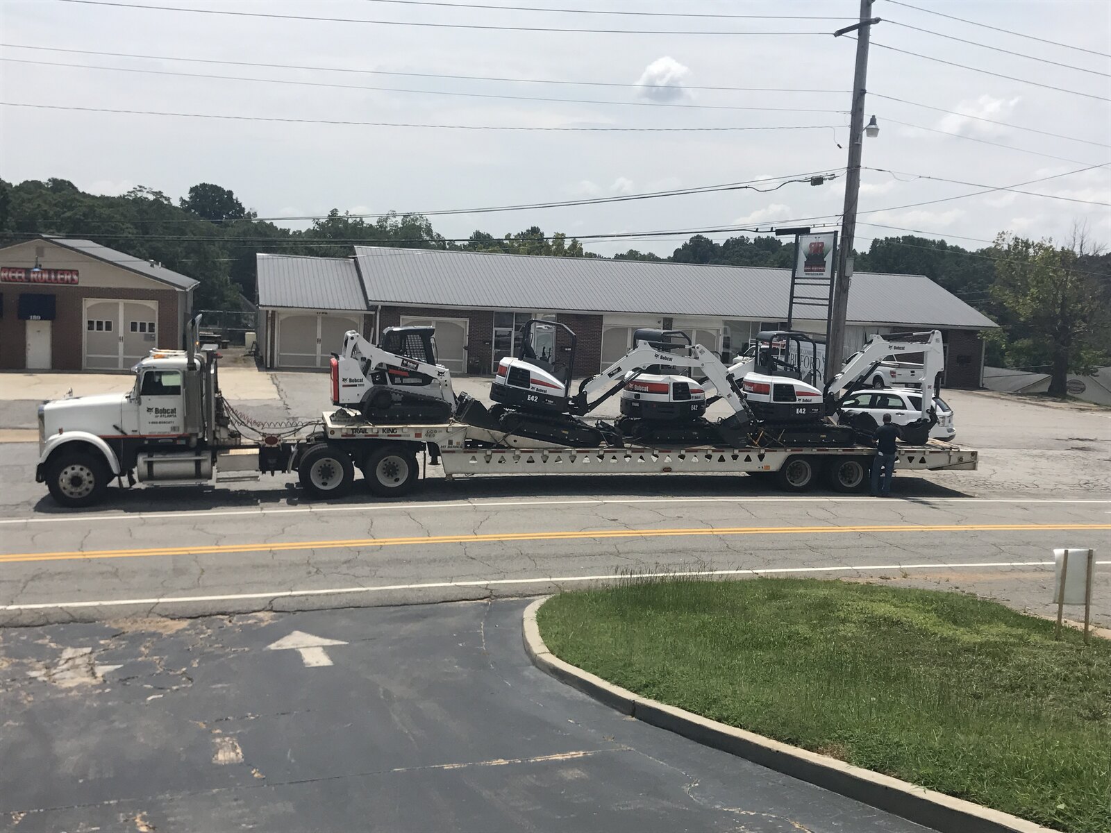Lowboy trailer loaded with mini excavators and a track loader delivered to the site