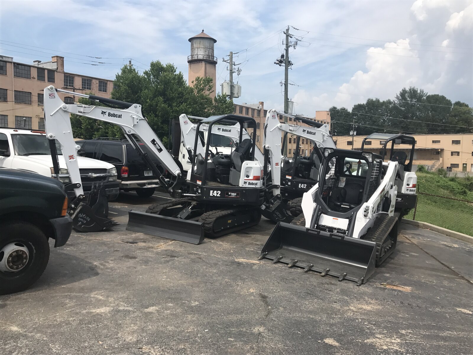 Mini excavators and a compact track loader staged in the company yard