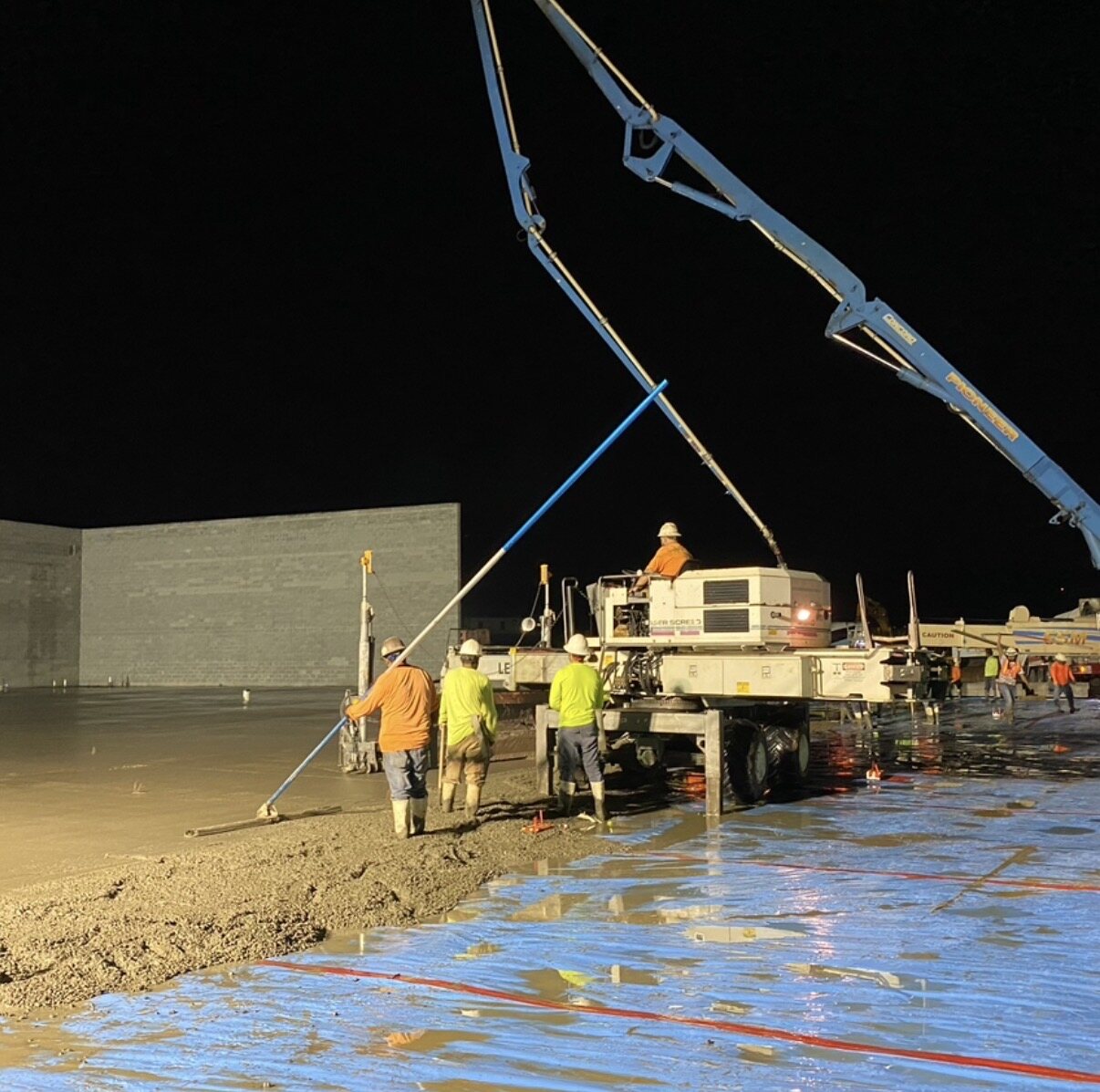 Night pour with boom pump and laser screed crew working under lights