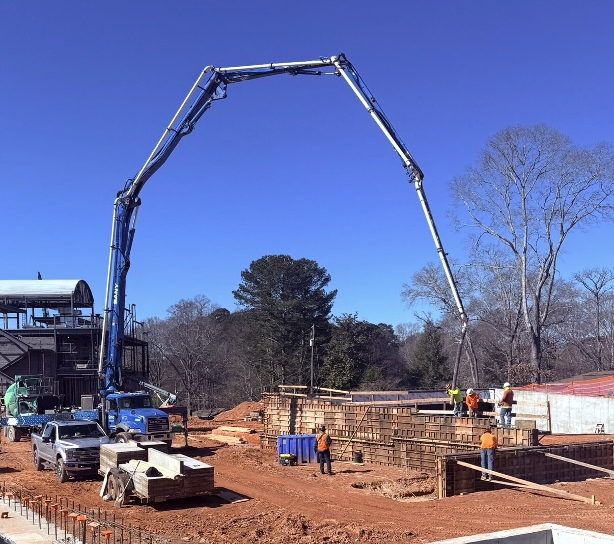 Boom pump arched over structural wall formwork against a clear sky