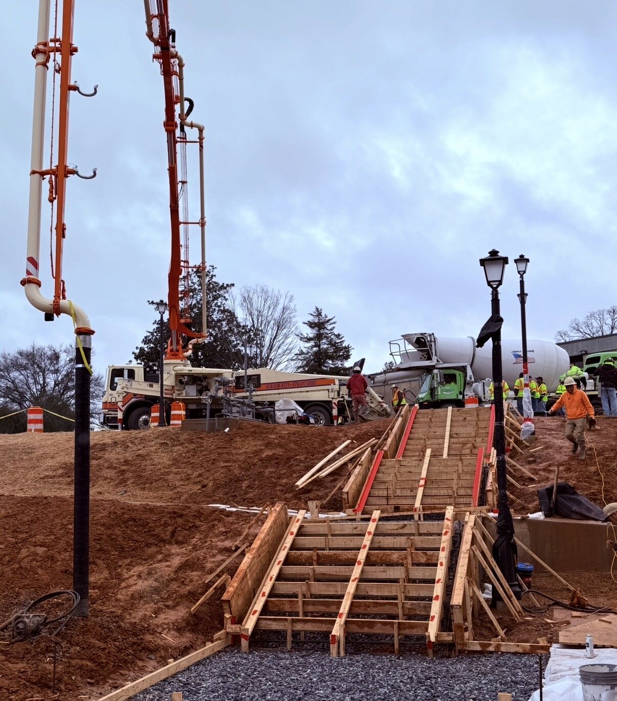 Stair formwork pour with pump booms and mixer trucks staged up the slope