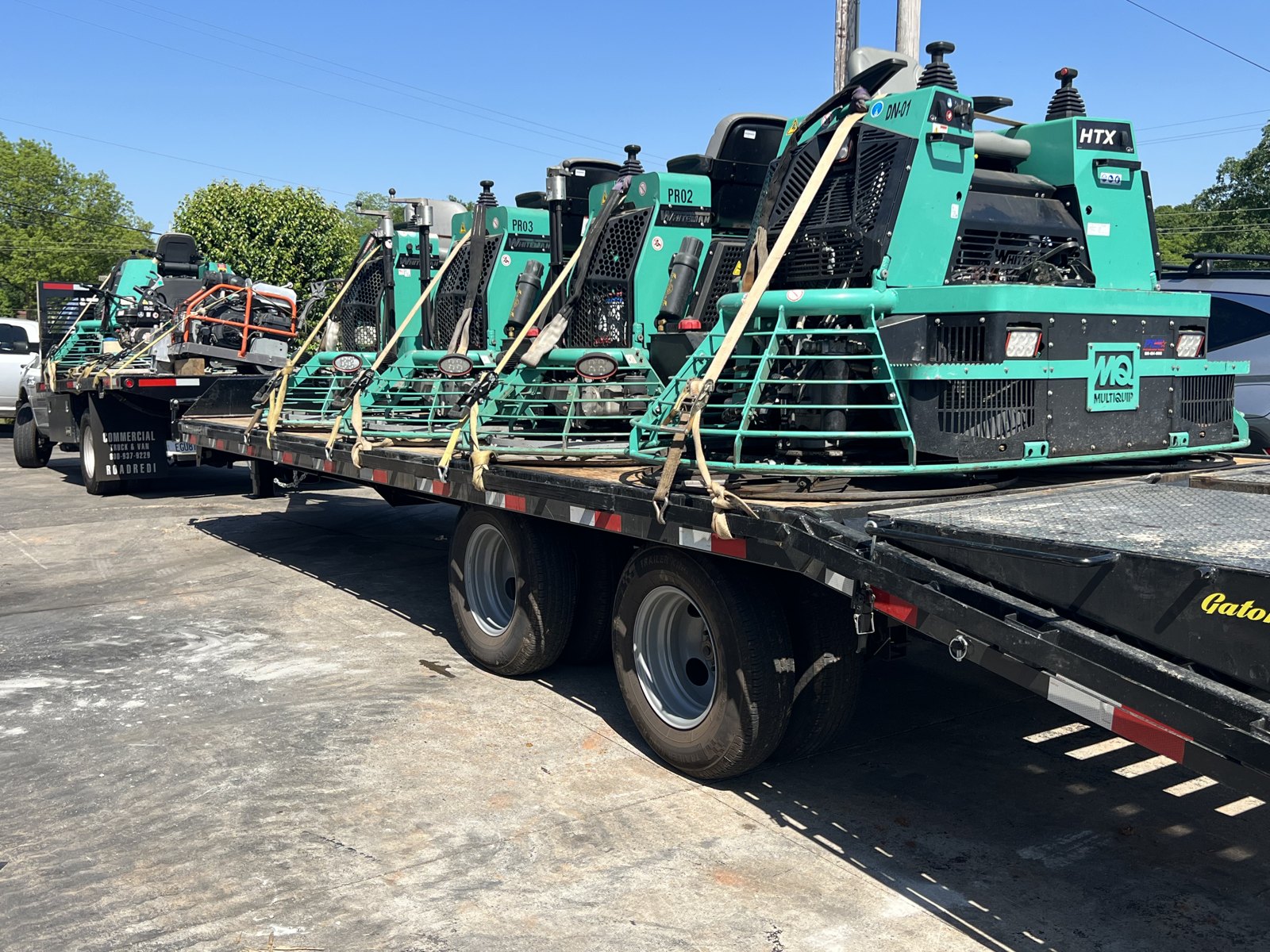 Ride-on power trowels strapped down on the trailer for transport