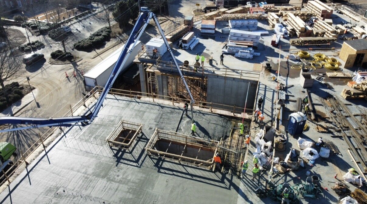 Aerial view of an elevated deck pour with boom pump, materials, and crews staged by SCI Management